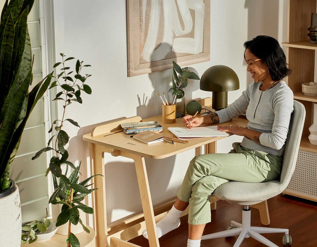 A smiling woman sits at her home office desk in her bright and clean home office workspace