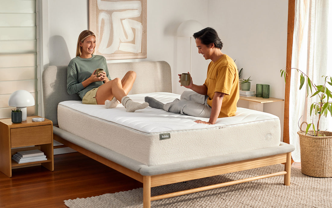 A couple sit on their bed in a bright and airy bedroom and discuss how to avoid farting while sleeping