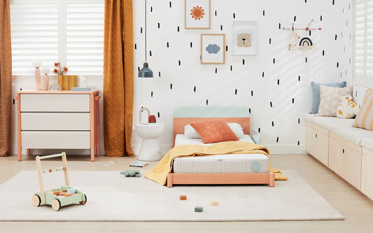 A large, colourful child’s bedroom filled with kids bedroom furniture such as a low bed, chest of drawers and a large rug
