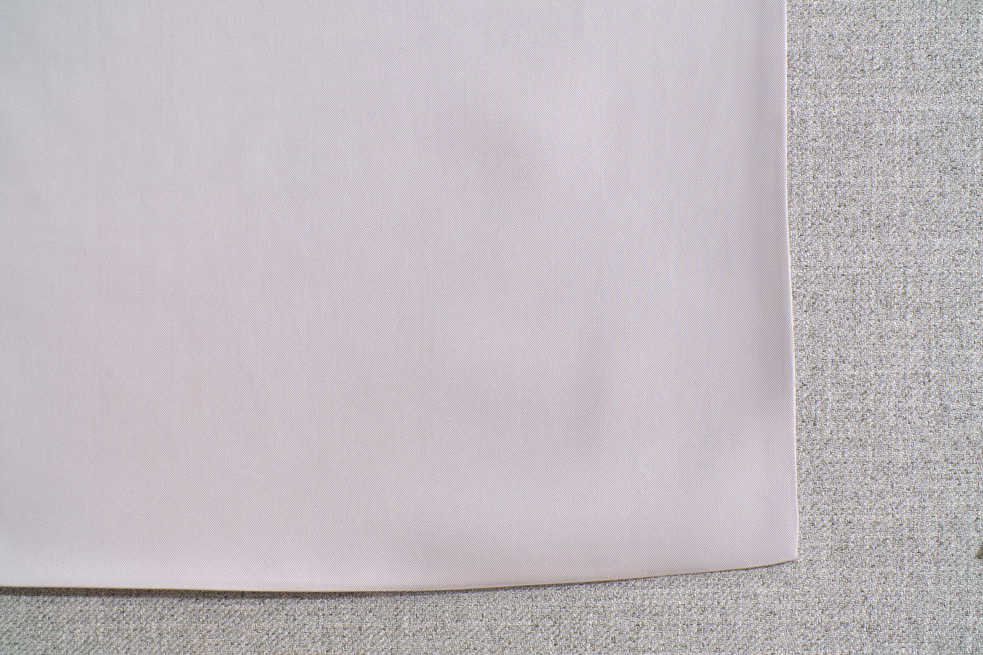 Close-up of a light grey fabric corner on a textured, darker grey surface.