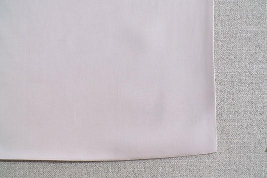 Close-up of a light grey fabric corner on a textured, darker grey surface.