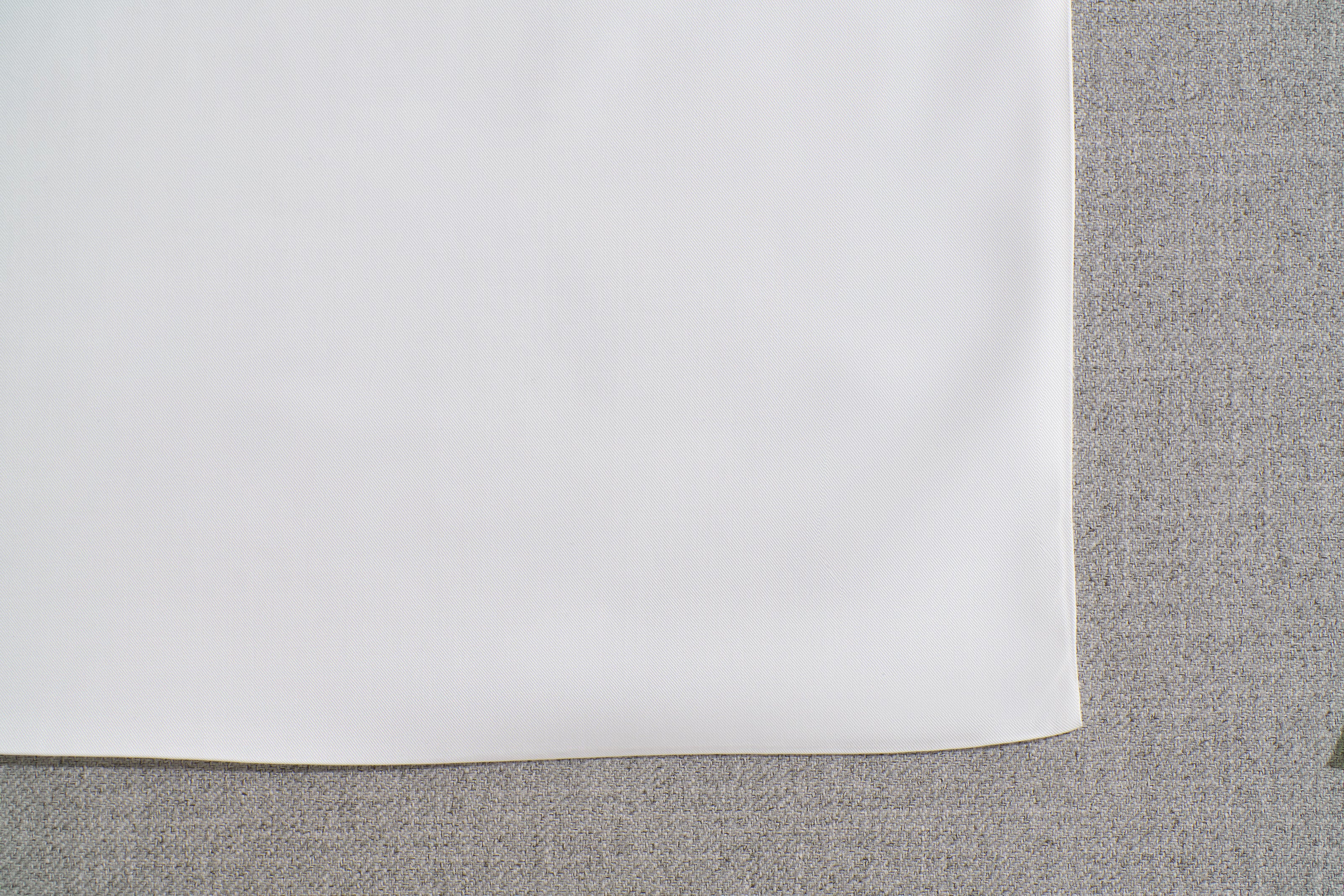 Close-up of white fabric on a light grey textured surface, showcasing contrast and texture.