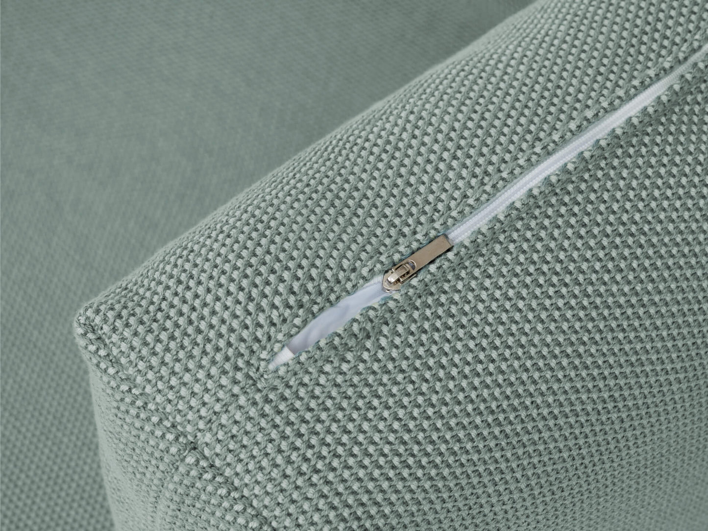 Close-up of a green textured cushion corner with a visible white zipper.
