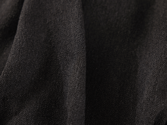 Close-up of textured dark grey fabric with subtle folds, ideal for upholstery or curtains.