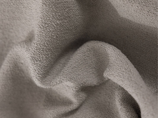 Close-up of soft, textured grey fabric with gentle folds, suitable for upholstery or interior design.