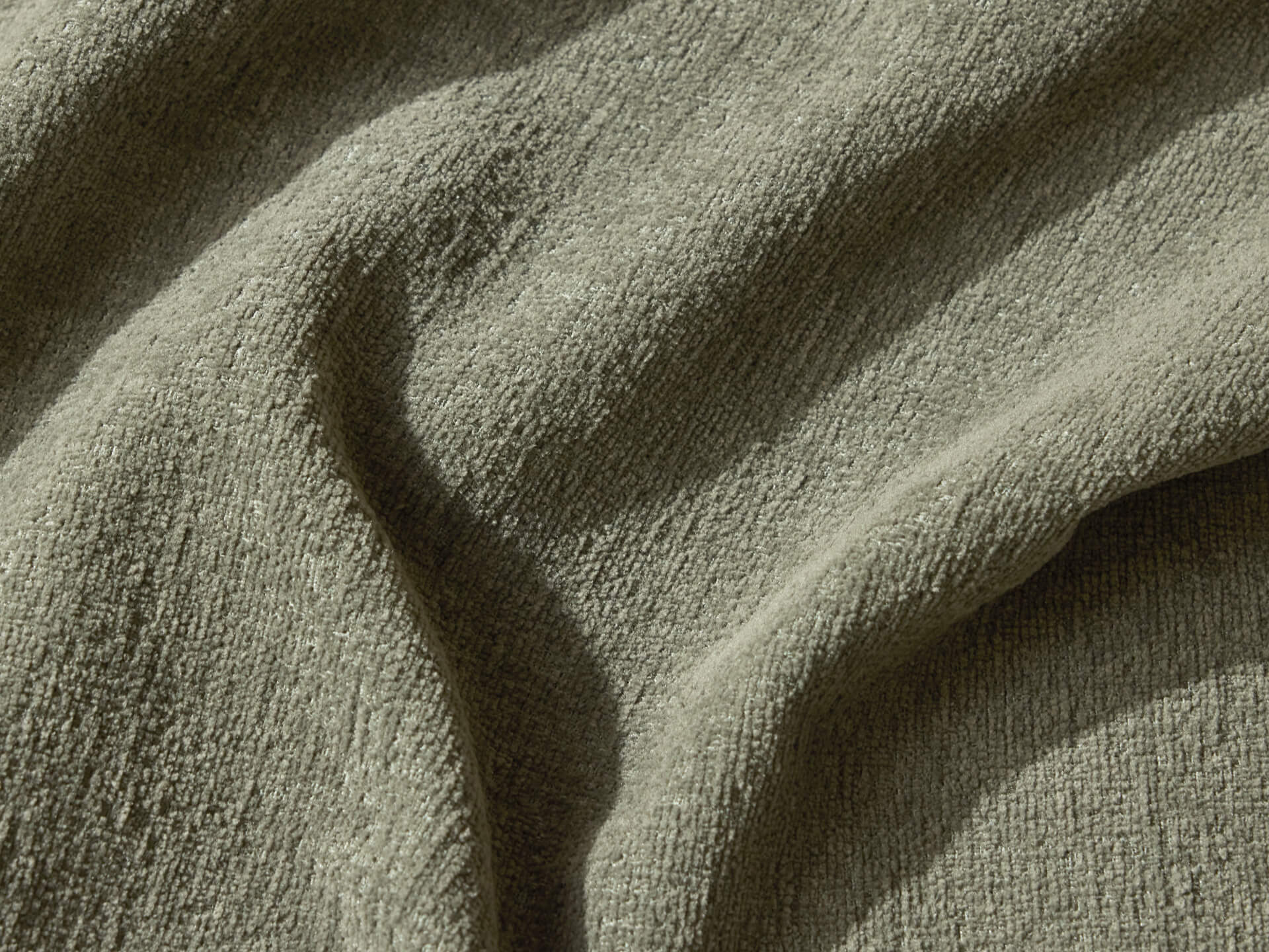 Textured olive green fabric with soft folds, highlighting a woven pattern. Ideal for upholstery or cushions in home décor.