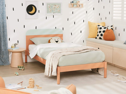 Stylish kids' bedroom with a light wood bed, mint green bedding, and polka dot cushions. Black and white wall pattern enhances modern decor.