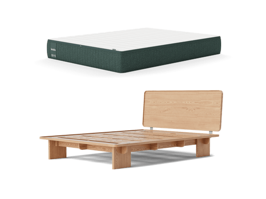 Mattress in dark grey and white next to a wooden platform bed frame with a tall headboard, isolated on a white background.