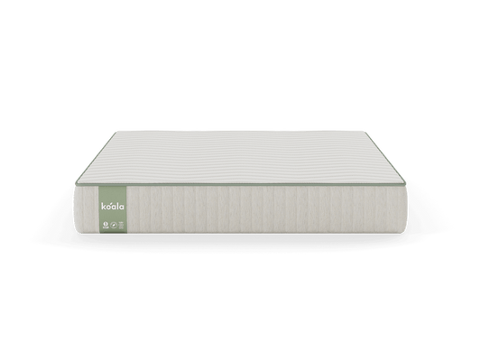 A white mattress with light grey sides, featuring a green label on the left corner, displayed against a green background.