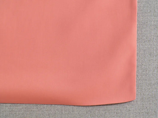 Coral fabric overlay on light grey textile background.