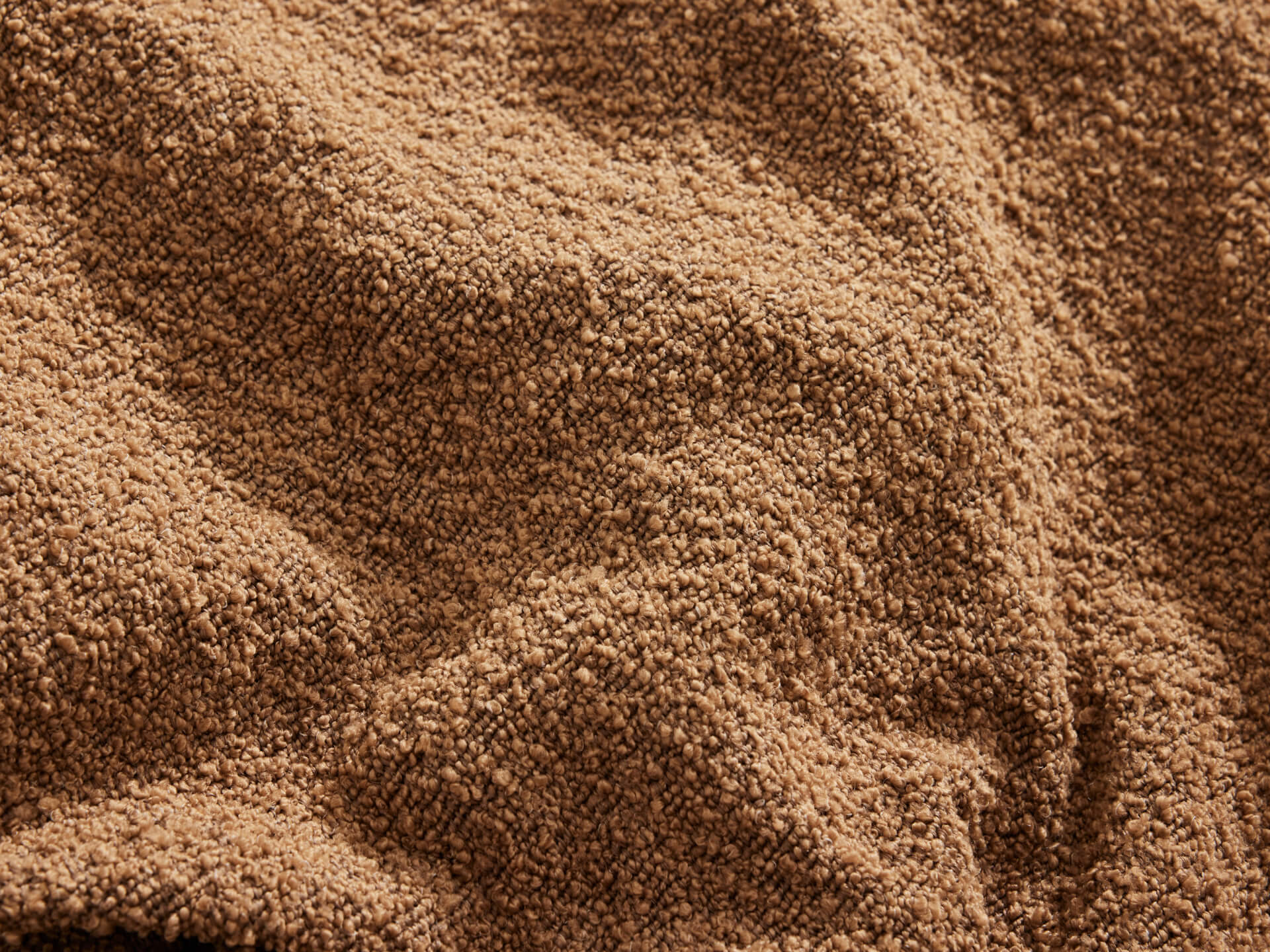 Textured brown fabric with a soft, plush surface and visible creases, ideal for upholstery or cosy home settings.