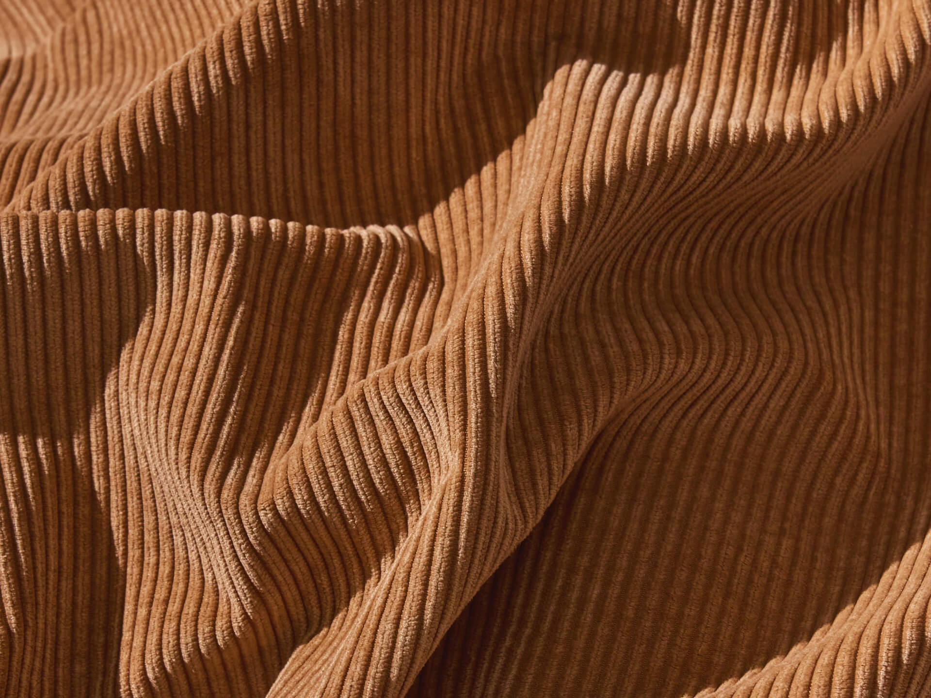 Close-up of crumpled brown ribbed corduroy fabric. Rich texture and warm colour, perfect for upholstery or autumn fashion.