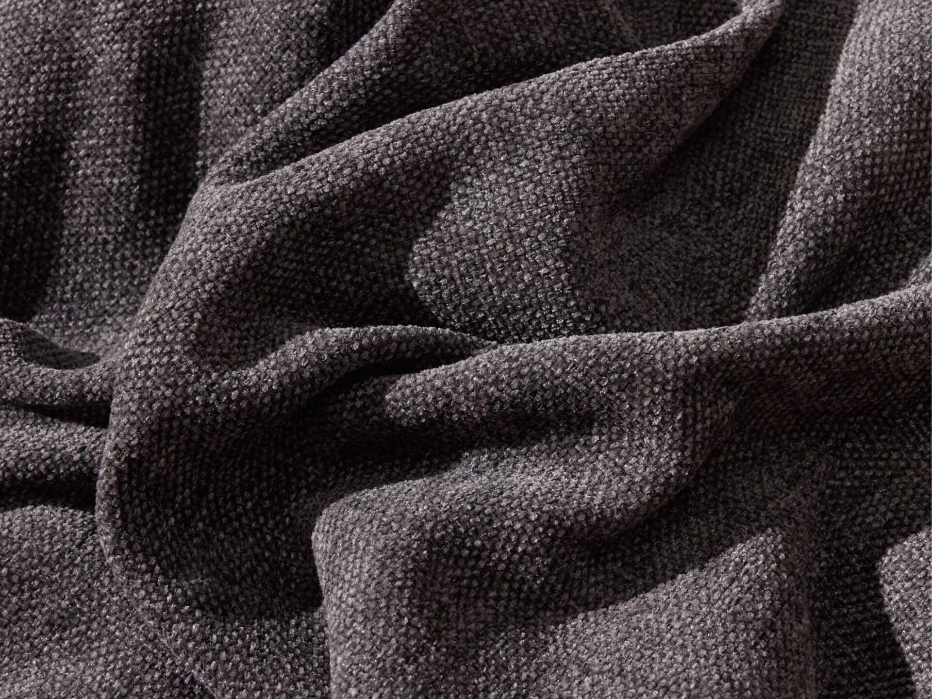 Dark grey textured fabric with a soft, draped appearance, ideal for upholstery or furniture, showcasing its tactile weave and rich colour.