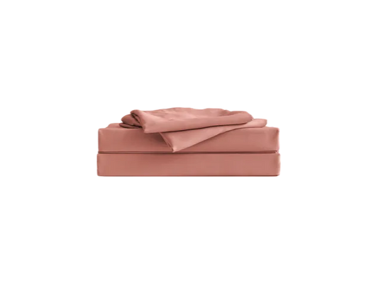 Folded pink sheet set on display, including fitted sheet, flat sheet, and pillowcase, arranged neatly.