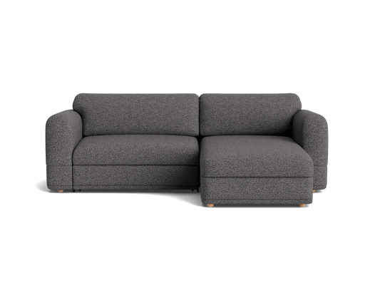 Dark grey fabric sectional sofa with a chaise on the right side. It features rounded armrests and wooden legs.