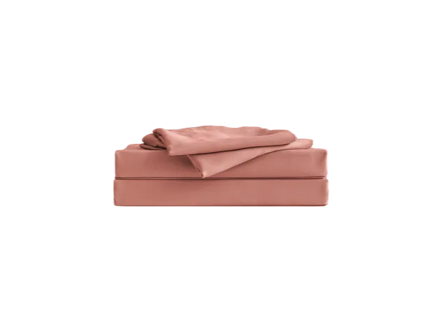 Folded pink bed sheets set neatly stacked on a white background.