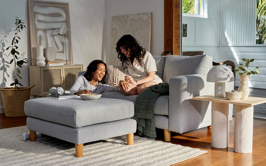 Two woman relax in a living room with sofa, rug and beautiful accessories