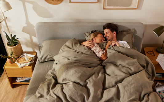 A smiling couple snuggle up on a Koala bed after discovering the secret to how to sleep better