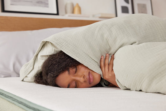 A woman resting peacefully on a firm mattress with her eyes closed in a comfortable sleeping position.