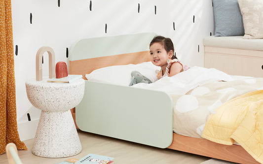 A small child wakes up in her toddler bed in her colourful bedroom