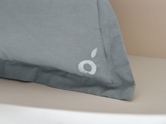Light grey pillow with a small white apple logo, on a beige background.