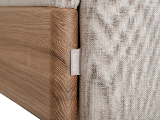 Close-up of a light grey fabric cushion against a light wood frame with a small tag. Perfect for modern Australian home décor.