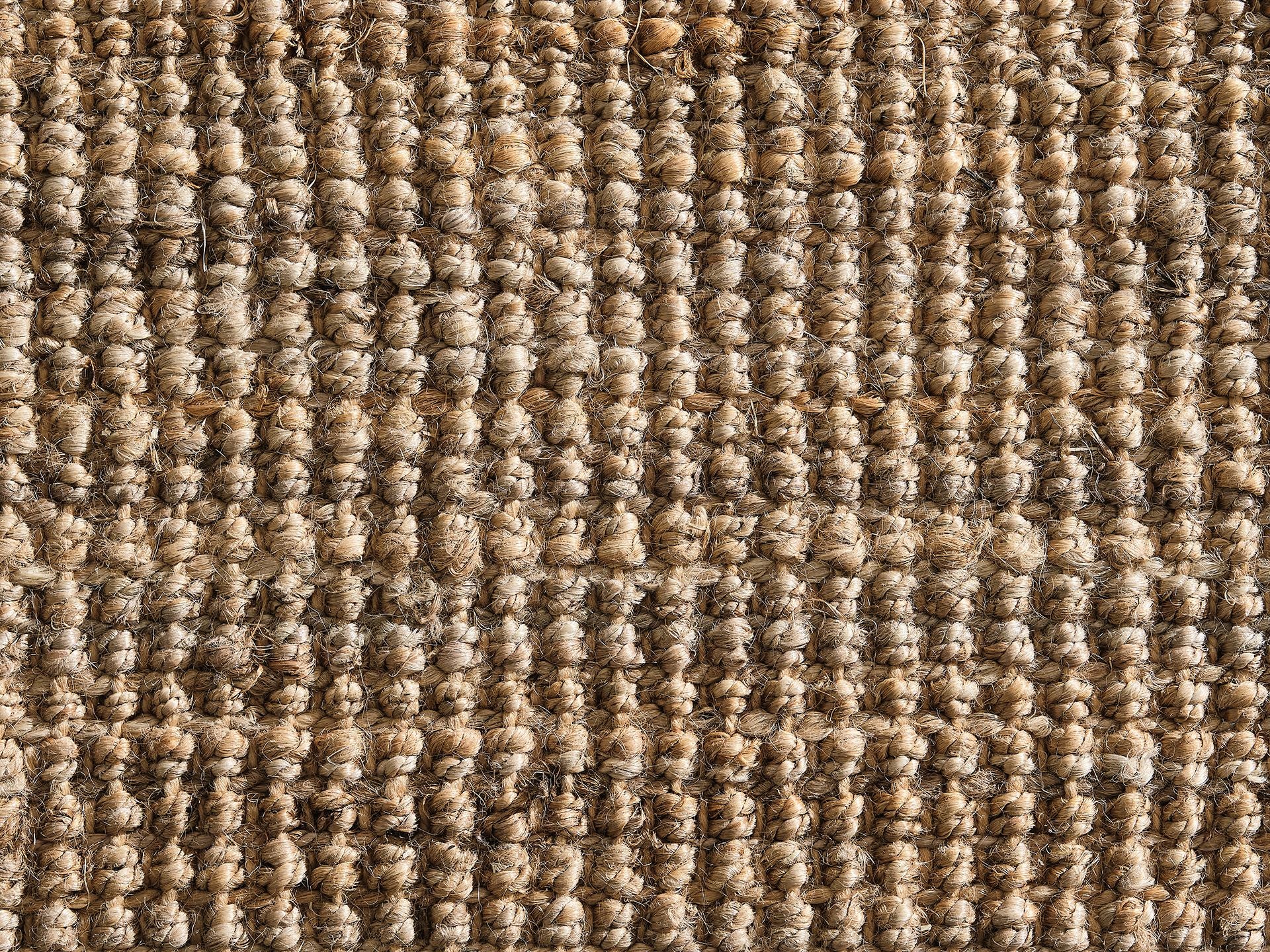 Close-up of textured beige woven carpet with a loop pile pattern. Natural fibres create a warm, rustic appearance. Ideal for cosy home interiors.