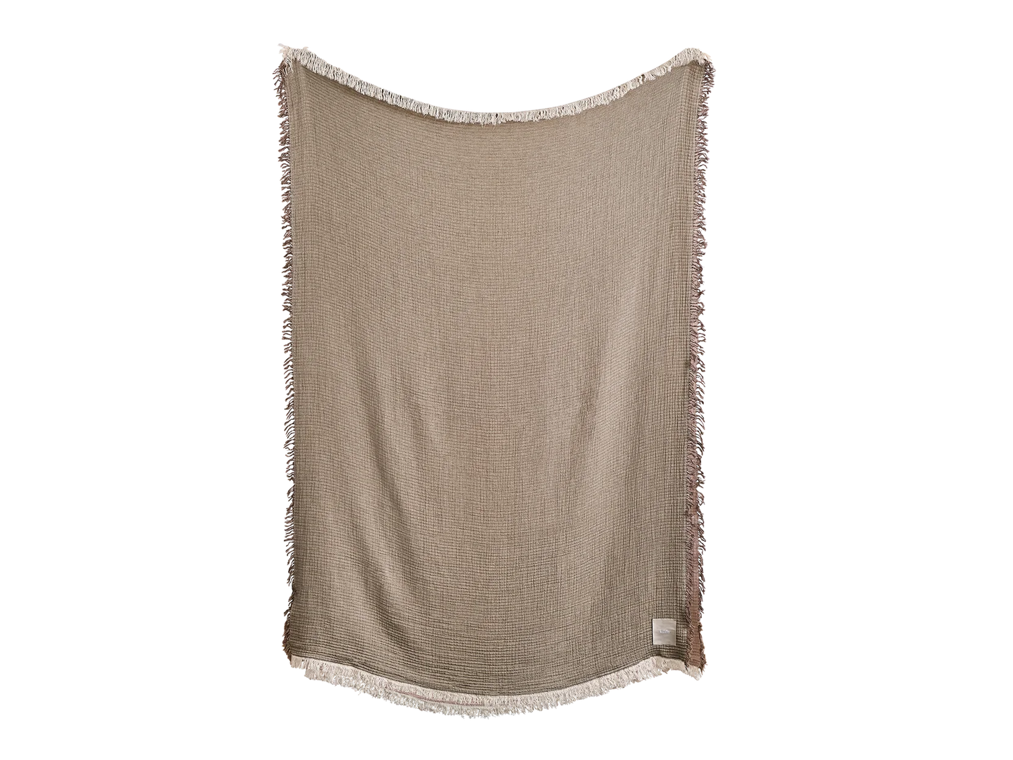 Beige textured throw blanket with white fringes on the edges, hung vertically. Simple and elegant home décor item.