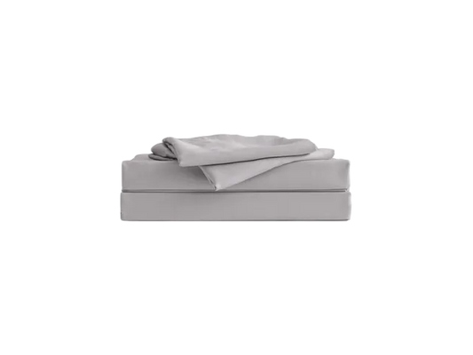 Neatly folded light grey sheet set placed atop its packaging on a plain background.