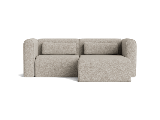 Beige modular sofa with two back cushions and chaise lounge on the right. Modern design, plush upholstery, clean lines, comfortable seating.