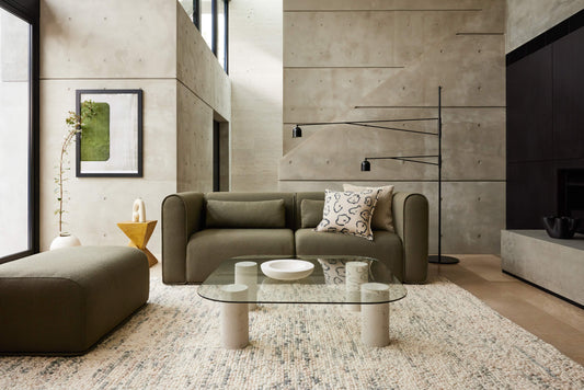 Olive green Koala modular sofa and ottoman in modern concrete living room with glass coffee table