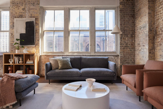 Grey Koala 2-seater sofa with matching ottoman and terracotta armchair in industrial loft with exposed brick