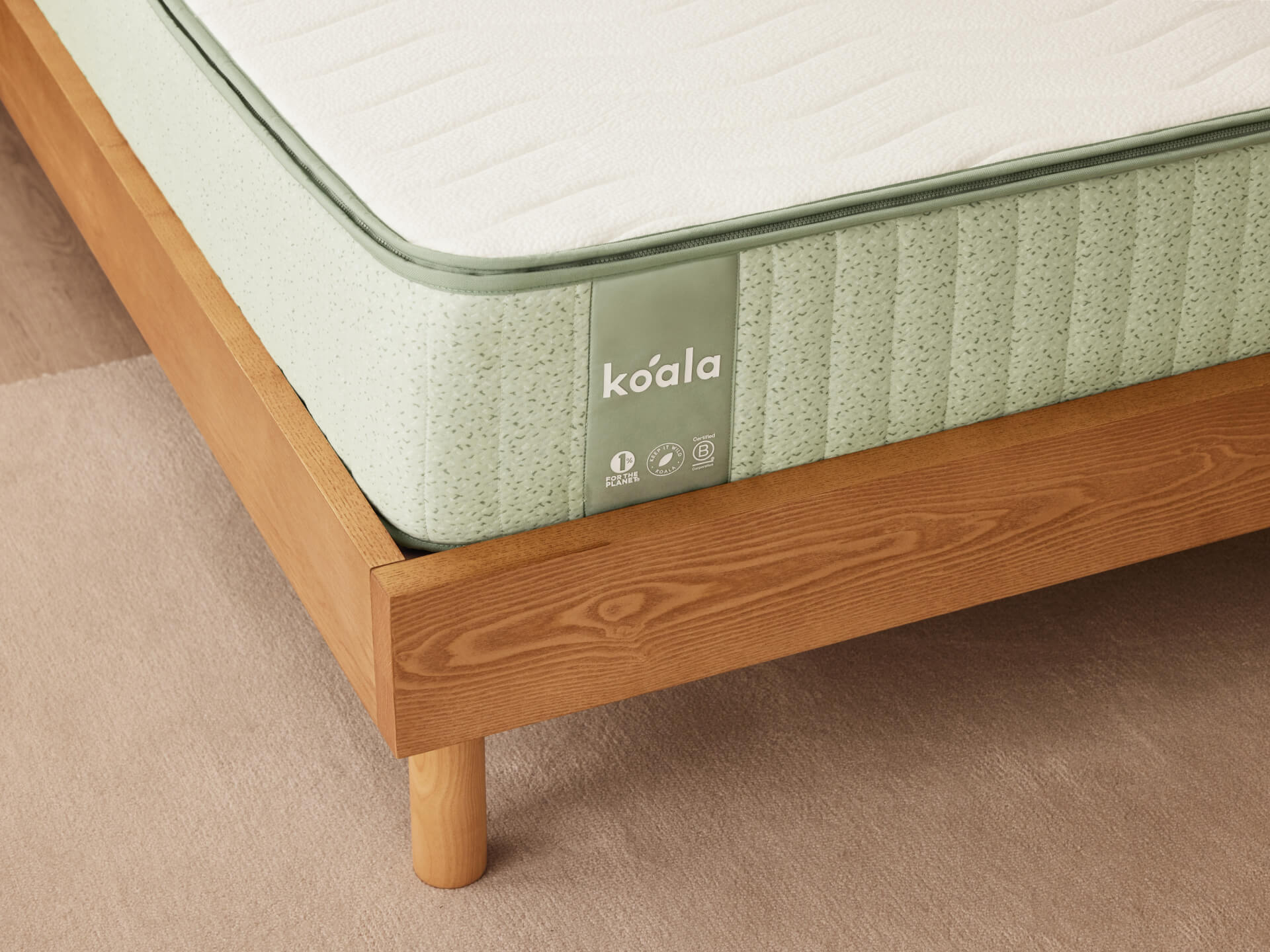 Light green mattress with a green trim on a wooden bed frame, showing the brand name "Koala".