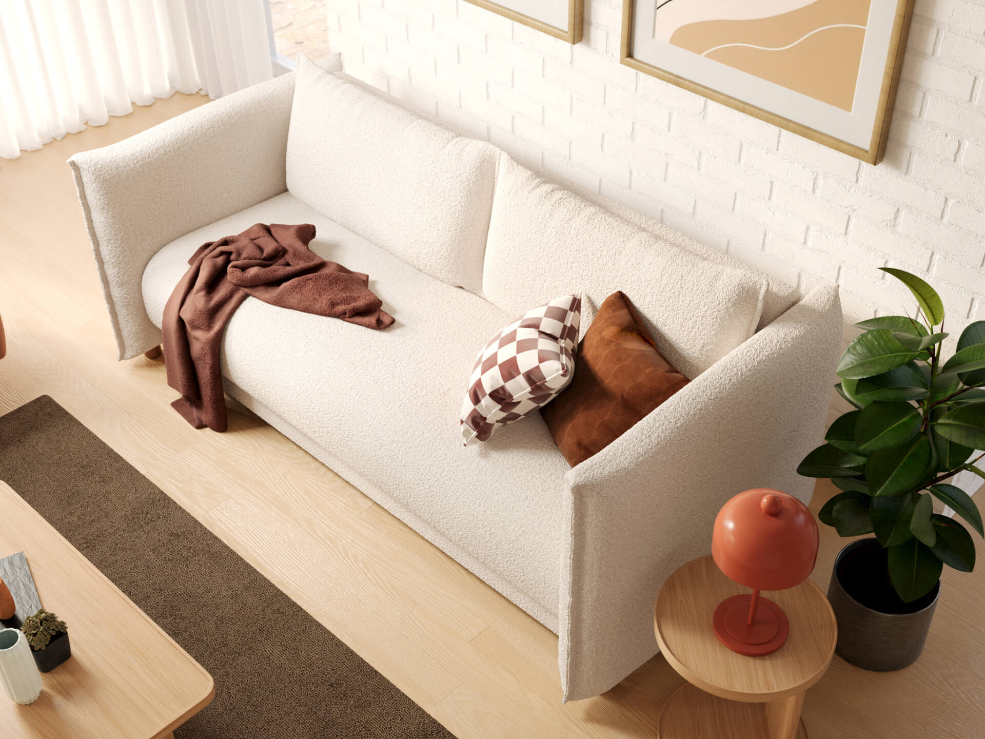 White couch with brown and checked cushions, brown throw, plant, and orange lamp on a side table. Light wood floor and wall art in background.