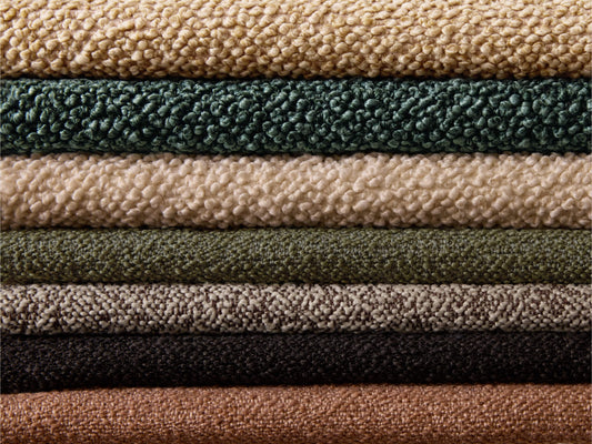 Stack of textured fabric swatches in beige, green, grey, black, and brown colours. Perfect for upholstery or interior design.