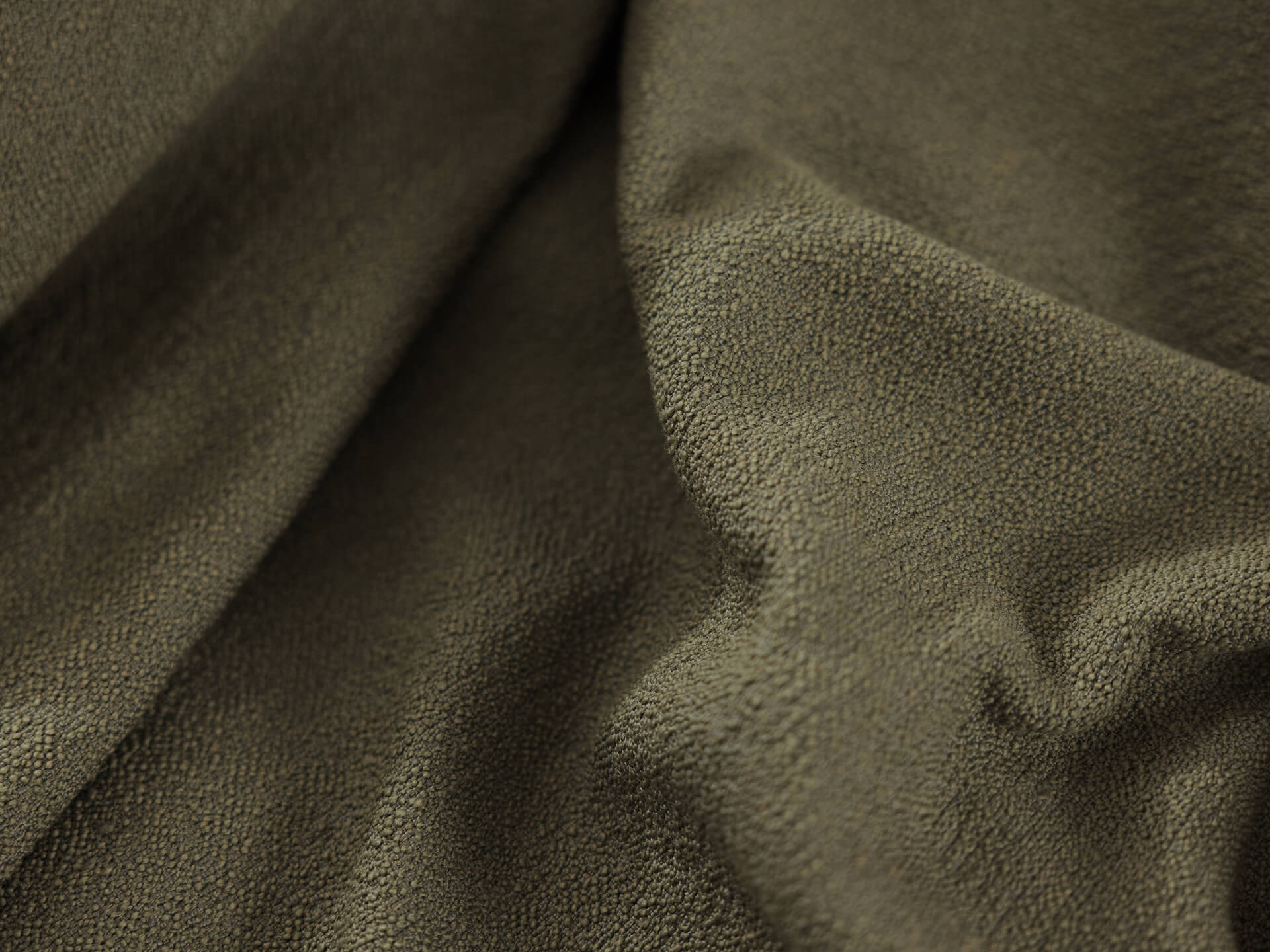 Close-up of olive green textured fabric with soft folds, suitable for upholstery or home décor.