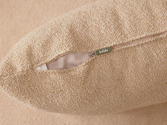 Close-up of a beige textured cushion with an open zipper, revealing a white inner lining and a metal zipper pull.