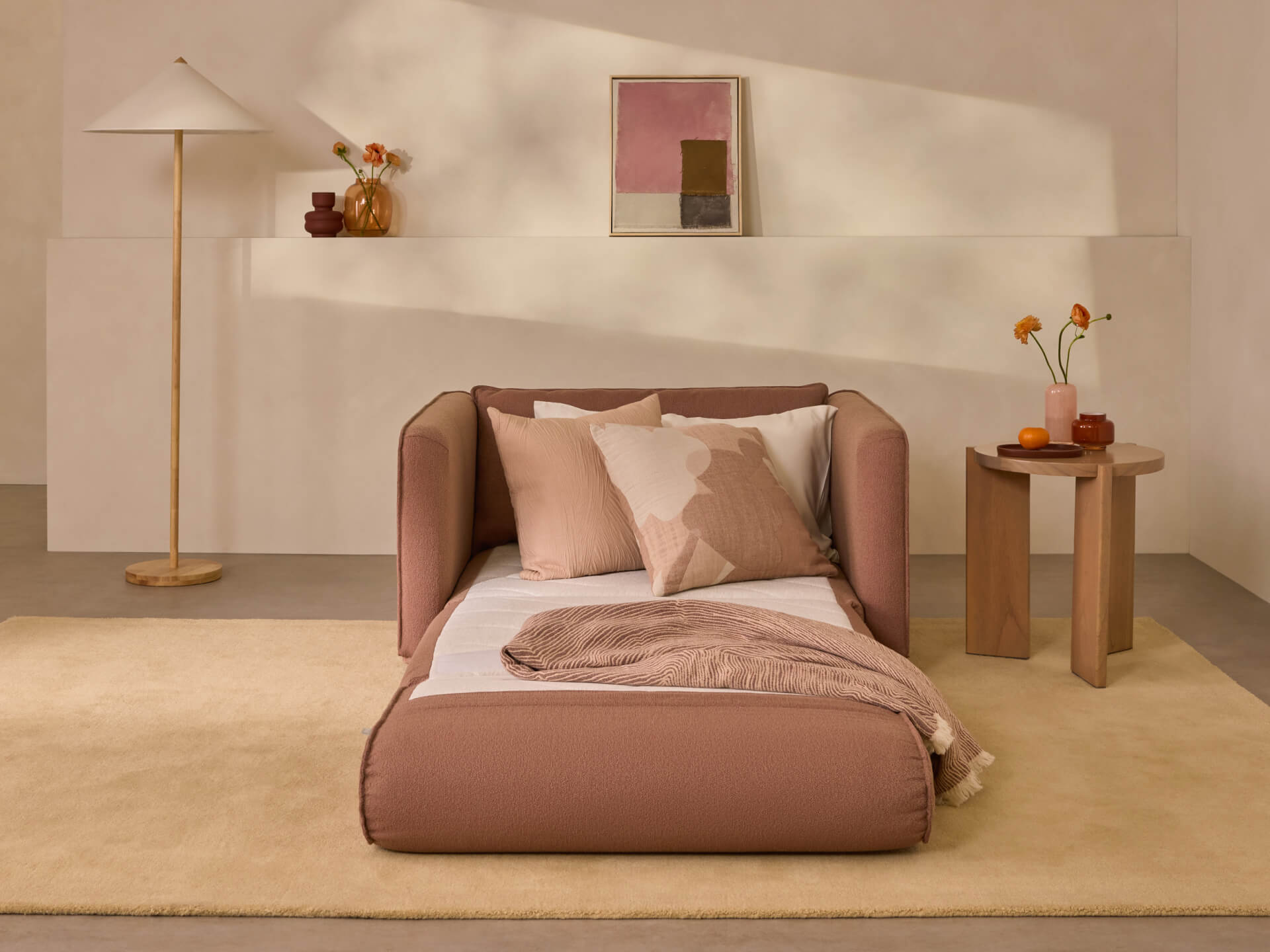 Modern living room with a beige chaise longue, two-tone cushions, a small side table, and a tall lamp. Neutral tones and minimalist decor.