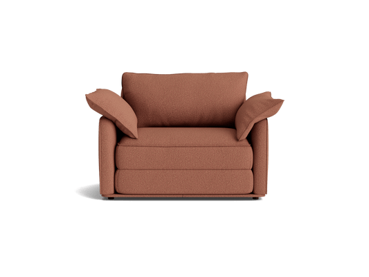 Rust-coloured cushioned armchair with plush backrest and armrests. Modern design, front view.