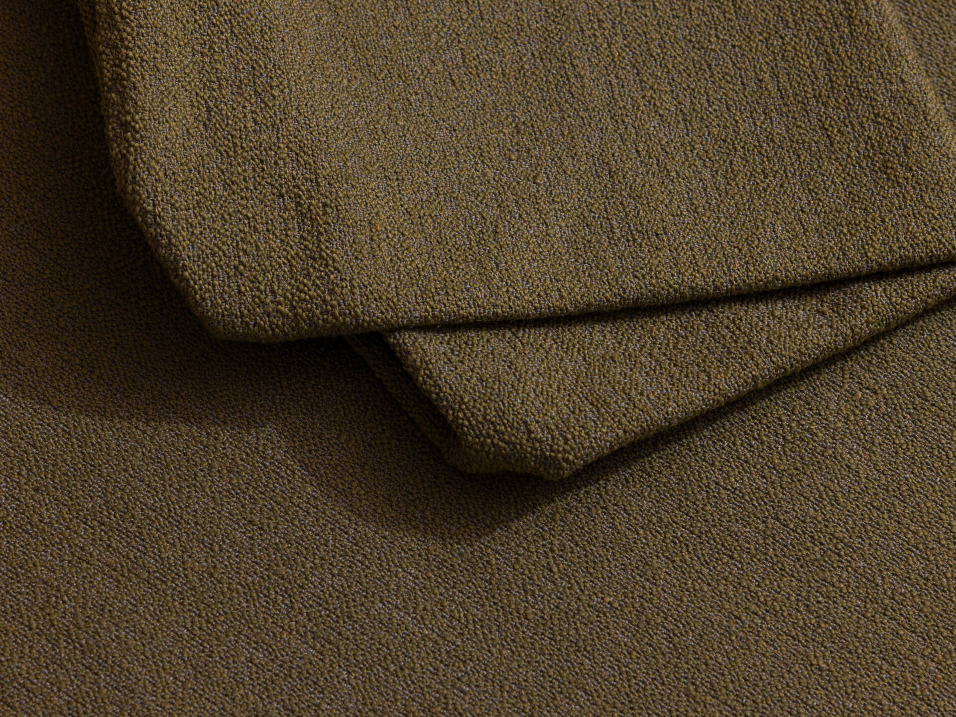 Close-up of olive green textured fabric, folded neatly.