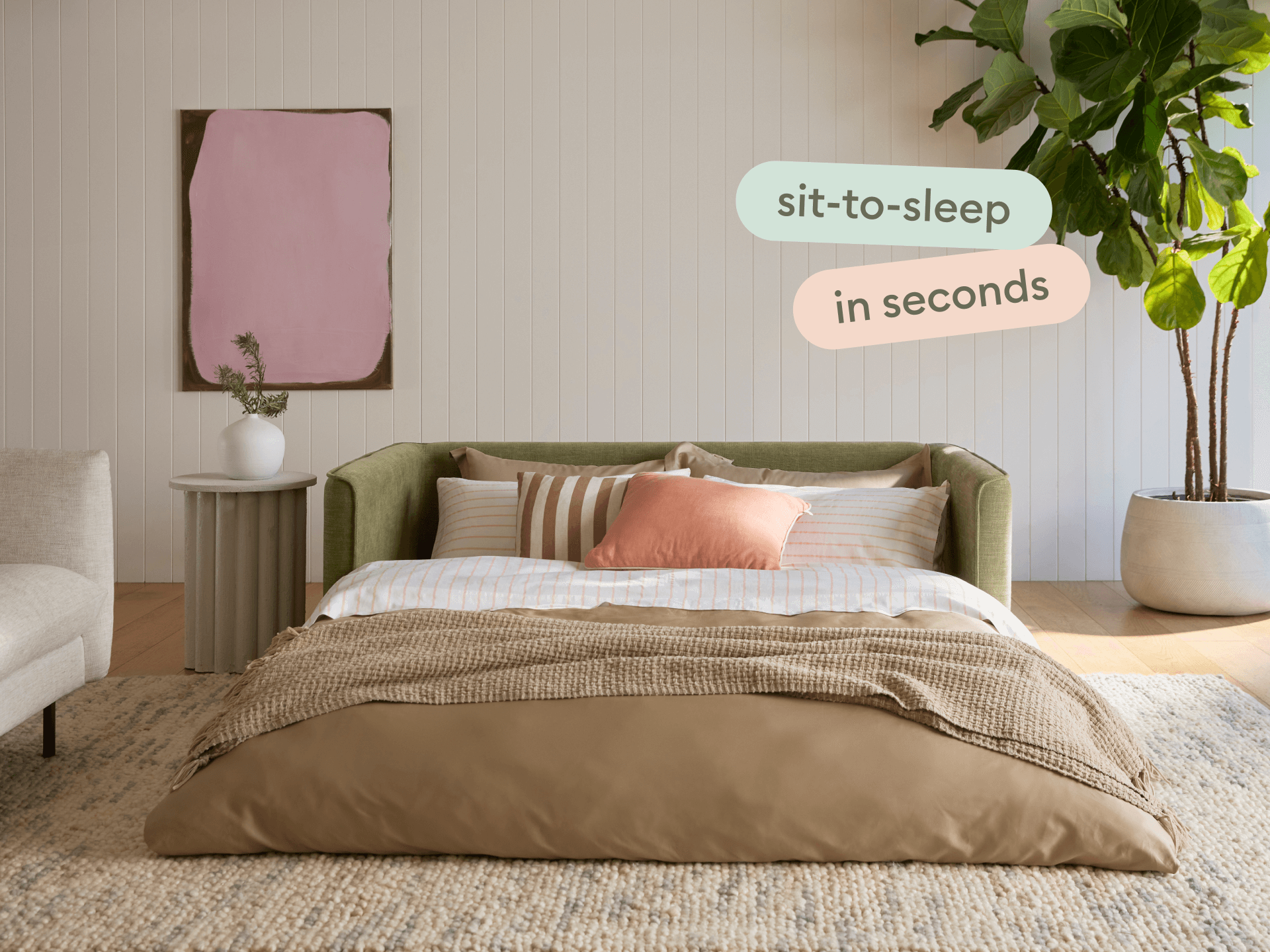 Luxurious green fabric sofa bed with sleek armrests, complemented by a tan duvet and striped pillows. Set in an elegant, light-filled room with a modern aesthetic.