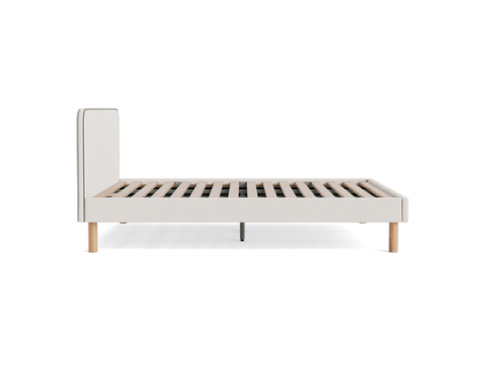 Side view of a light grey upholstered bed frame with wooden slats and light wooden legs on a white background.