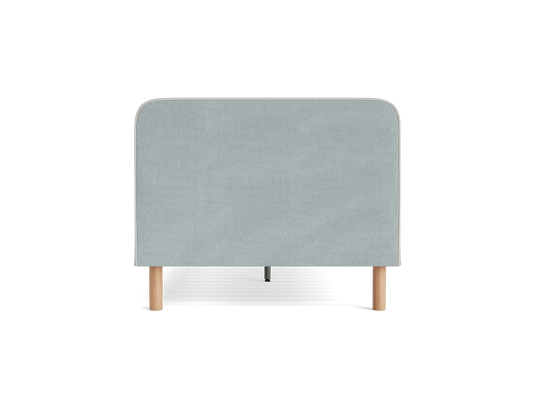 Light grey upholstered headboard with rounded corners, supported by four light wooden legs.
