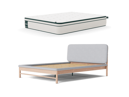 White mattress with dark trim above a light wood bed frame, featuring a grey fabric headboard.