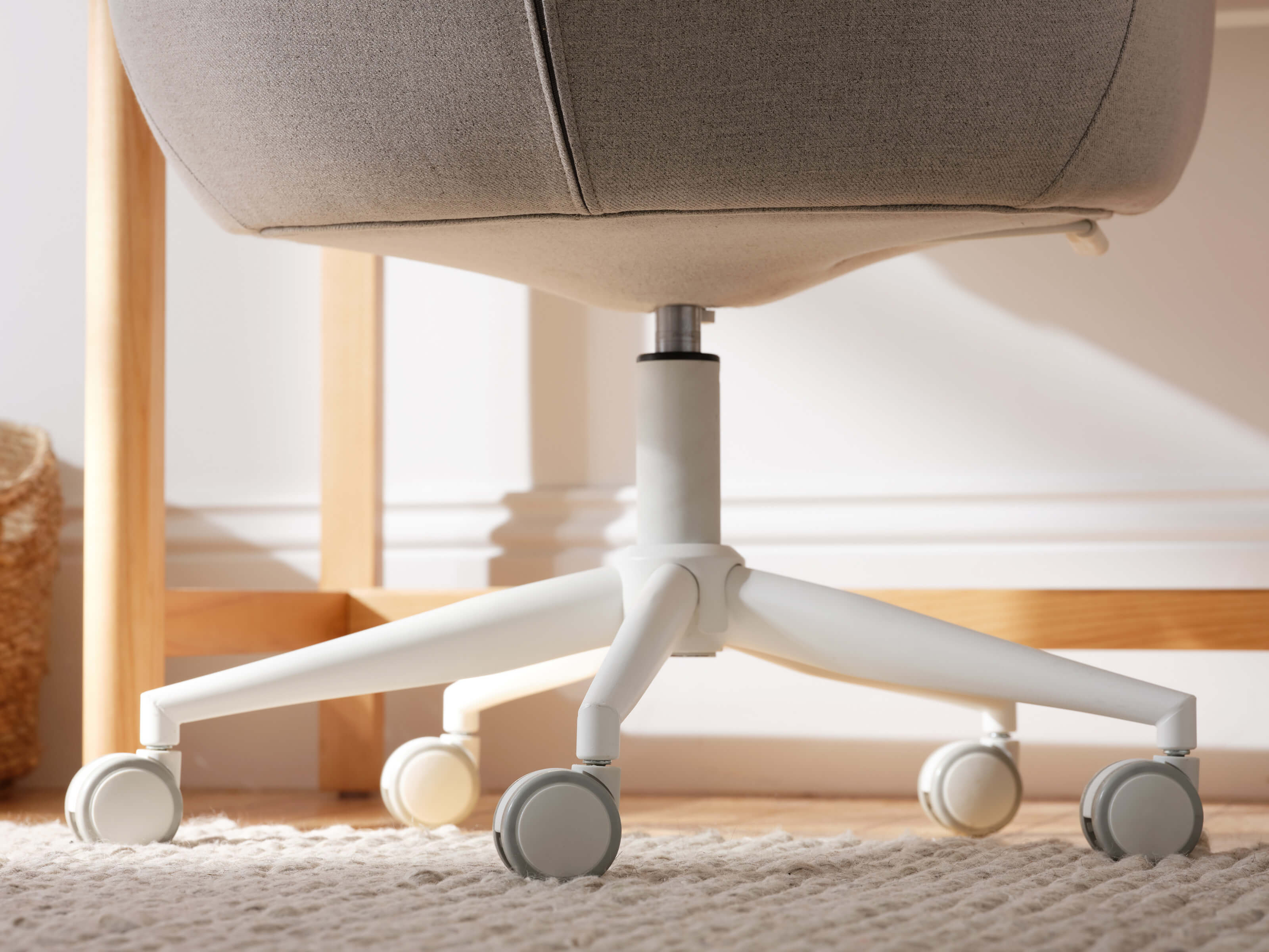 Grey office chair with white wheels on a light carpet. Wooden frame visible in the background.