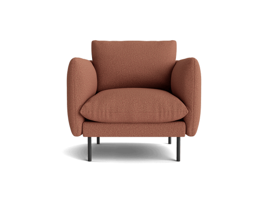 Brown armchair with plush cushions and tubular metal legs, viewed from the front. Comfortable modern furniture design.