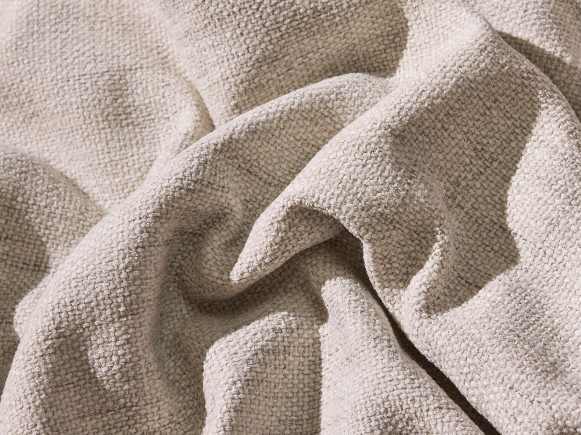 Beige textured fabric with visible weave pattern, casually crumpled, highlighting its soft and natural look.