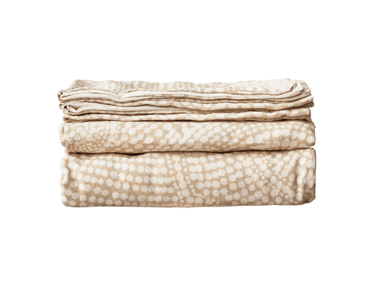 Folded beige blanket with a white polka dot pattern on a white background.