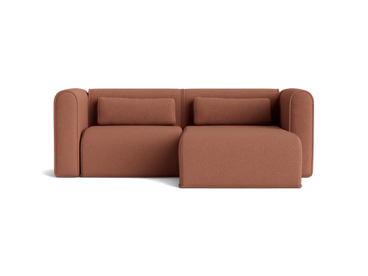 Rust brown sofa with two cushions and an attached chaise lounge. Modern design with rounded armrests.