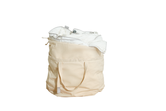 Beige canvas laundry bag filled with white fabric, featuring handles and an external pocket.